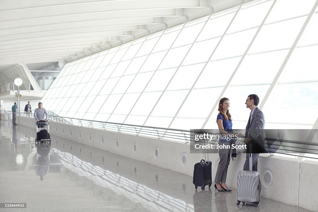 Man and woman talk waiting with luggage at airport