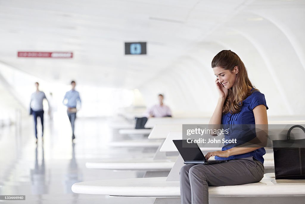 WOMAN USING TECHNOLOGY ON THE MOVE AT THE AIRPORT