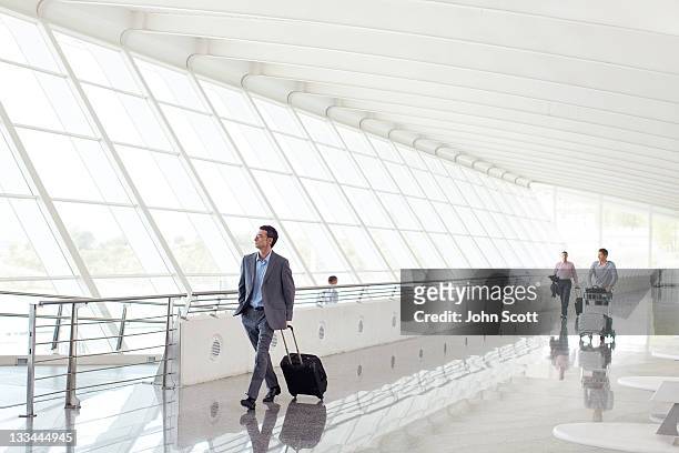 businessmen walking with luggage at airport - flughafen stock-fotos und bilder