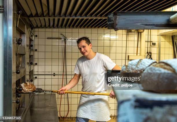 baker taking bread out of oven - artisanal food and drink stock pictures, royalty-free photos & images
