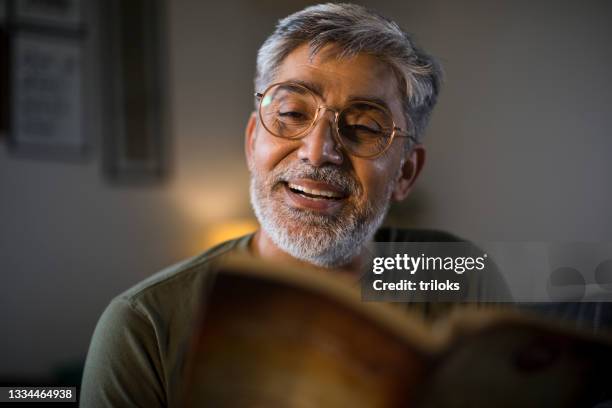 man reading book at home - leesbril stockfoto's en -beelden