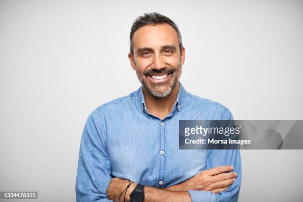 confident mature hispanic man against white background - portretfoto stockfoto's en -beelden