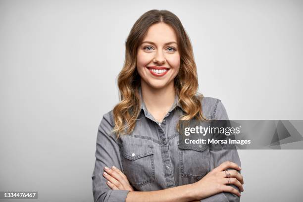 smiling woman with arms crossed against white background - gray shirt stock pictures, royalty-free photos & images