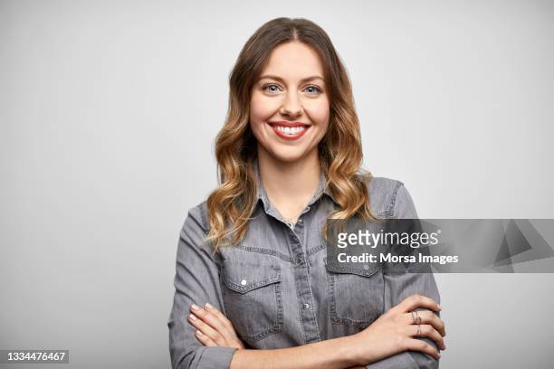 smiling woman with arms crossed against white background - camisa cinzenta - fotografias e filmes do acervo