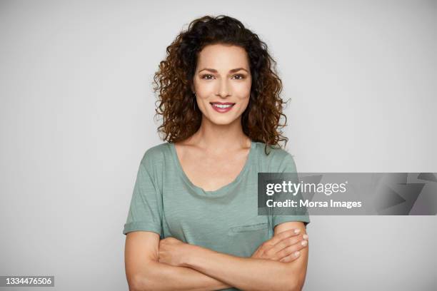 smiling young woman in t-shirt against white background - golvend haar stockfoto's en -beelden