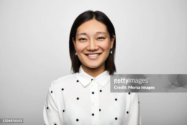 confident chinese businesswoman against white background - portrait grey background stock-fotos und bilder