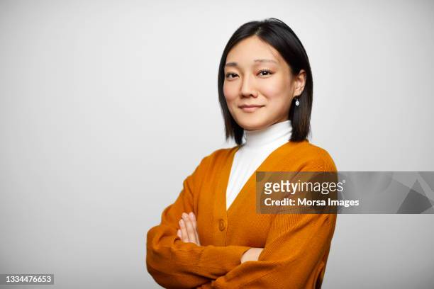 confident chinese businesswoman against gray background - cardigan sweater photos et images de collection