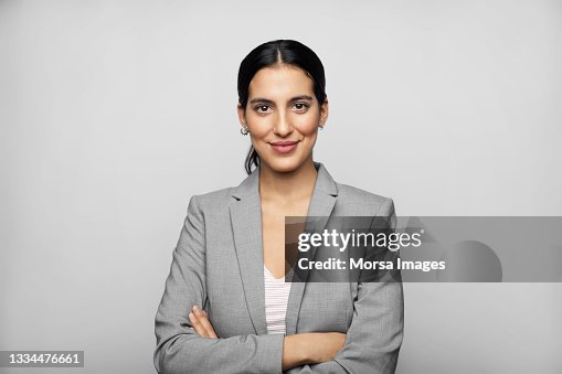 Latin American Businesswoman In Blazer Against Gray Background Latin American Businesswoman In Blazer Against Gray Background