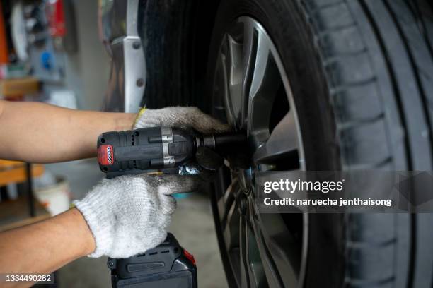 detail image of mechanic hands with tool, changing tyre of car, with blurred background of garage. - limousine stock pictures, royalty-free photos & images