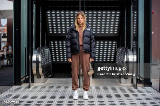 Alessa Winter wearing black North Face puffer jacket, brown jumper, Gucci bag, white sneaker Copenhagen Studios, brown jogger pants on August 12,...