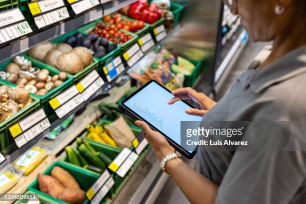 supermarket employee taking inventory of produce section - groceries tablet stock pictures, royalty-free photos & images