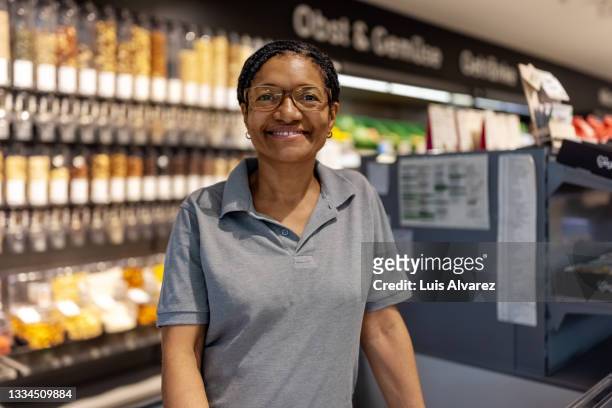 portrait of confident female supermarket cashier - female supermarket stock-fotos und bilder