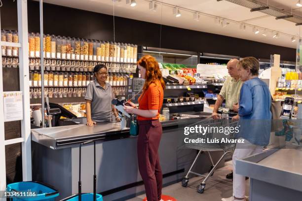 people at supermarket checkout counter - grocery checkout stock pictures, royalty-free photos & images