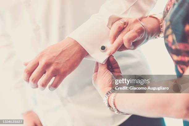 groom mother putting the wedding cufflinks on her son's shirt, lombardy, italy - cufflinks stockfoto's en -beelden