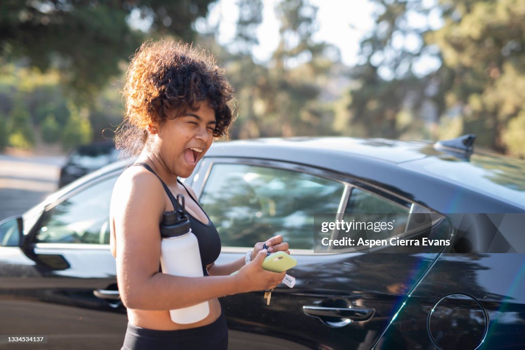 Woman by car in workout clothes