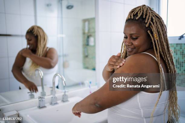 mulher afro-americana em sua rotina diária de cuidados com a pele no banheiro. - no ombro - fotografias e filmes do acervo
