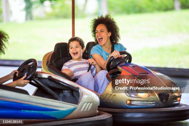 eine glückliche afroamerikanische familie hat spaß im vergnügungspark. - autoscooter stock-fotos und bilder