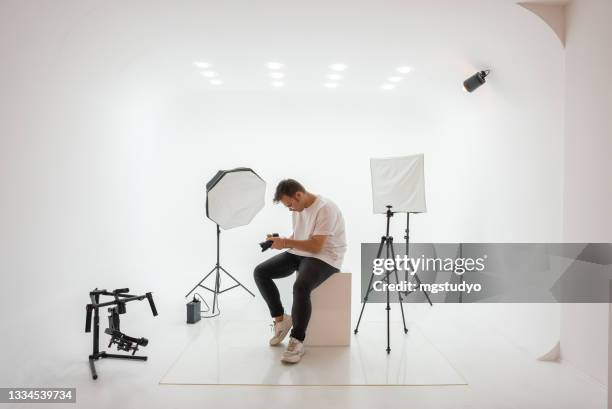 joven fotógrafo eligiendo foto en estudio. - sesion fotografica fotografías e imágenes de stock