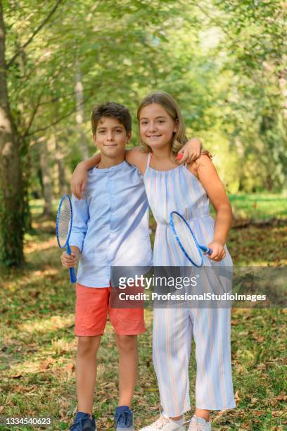 a young boy is ready to play badminton at the playground with his cute little sister. - sweet little models stock pictures, royalty-free photos & images