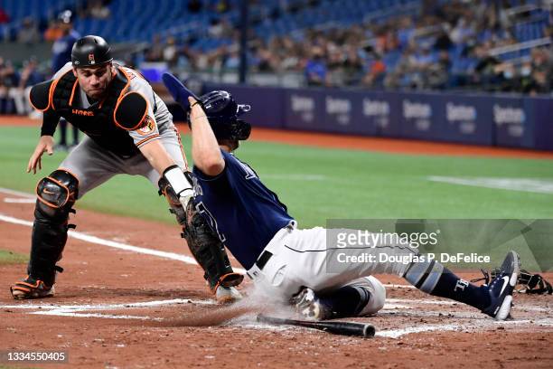 Austin Wynns of the Baltimore Orioles tags out Austin Meadows of the Tampa Bay Rays at home plate in the fourth inning at Tropicana Field on August...