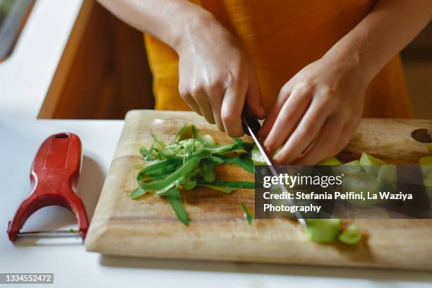 close up on child's hands while cutting a cucumber with a knife - éplucher photos et images de collection