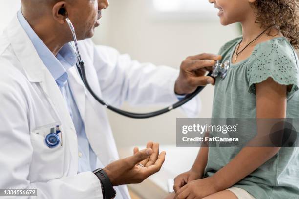 doctor using a stethoscope to examine a young girl's chest - 遮蔽的面孔 個照片及圖片檔