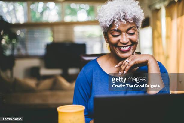 cheerful woman on video call at home - mature woman fotografías e imágenes de stock