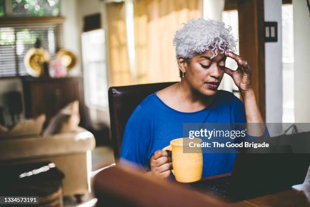 stressed out woman working at laptop on table at home - head aches stock pictures, royalty-free photos & images