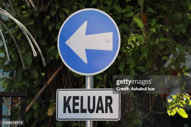 an arrow sign for "keluar" which means exit - indonesia bikes traffic stockfoto's en -beelden