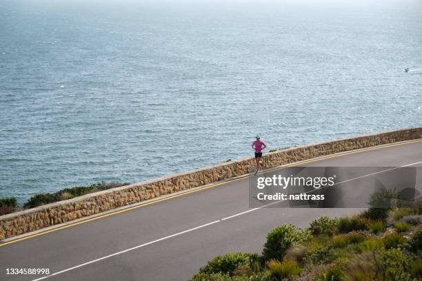 woman running along coastal road near cape town - will cape town run out of water stock pictures, royalty-free photos & images