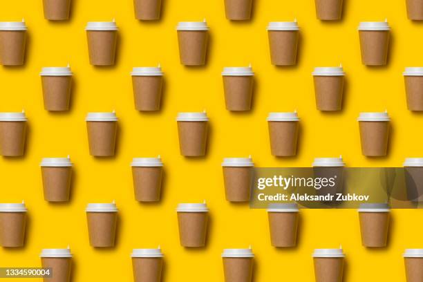 a disposable paper cup with a lid for coffee and tea on a bright pastel yellow background. coffee break. seamless background or texture, pattern and wallpaper. the concept of environmental protection. copy the space. - coffee cup takeaway stock-fotos und bilder