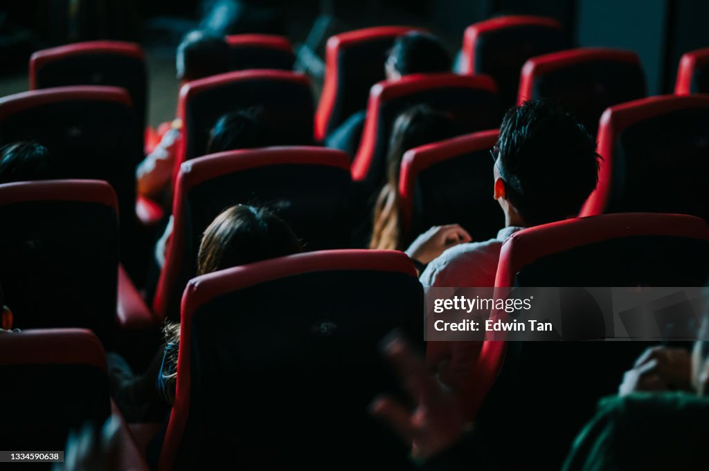 Rear view asian chinese group of audience watching 3D movie in cinema enjoying the show with 3D glasses screaming excitement