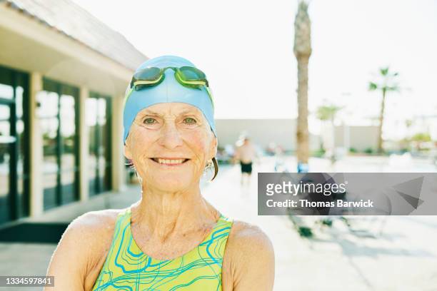 Medium close up shot portrait of smiling senior female athlete standing on pool deck before swimming morning workout