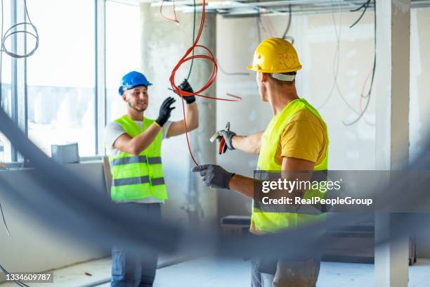 two electrician builder engineers workers installing industrial cable - electrician apprentice stock pictures, royalty-free photos & images