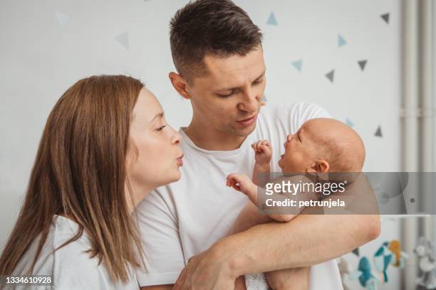 happy family with newborn baby - moms crying in bed stockfoto's en -beelden