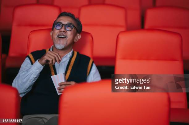 asian chinese active senior man enjoying his snack while watching movie in movie theater cinema alone - film premiere stock pictures, royalty-free photos & images