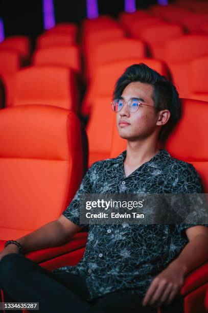 asian chinese teenage boy watching movie in movie theater cinema alone with blank facial expression - asian cinema stock pictures, royalty-free photos & images