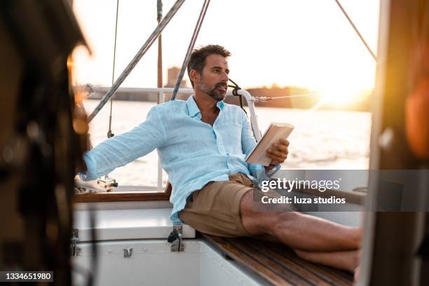 reading a book on the sailboat - man sailing stock pictures, royalty-free photos & images