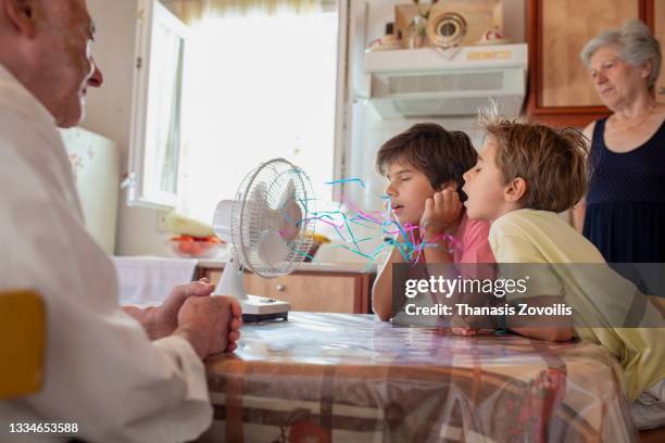 boys standing in front of a fan and enjoy cool waves - electric fan stockfoto's en -beelden