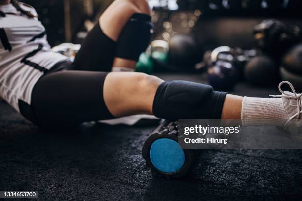 young woman massaging calf in gym - female muscular calves stockfoto's en -beelden