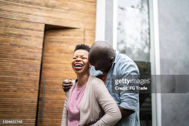 happy couple embracing in front o new house - candid moments stock pictures, royalty-free photos & images