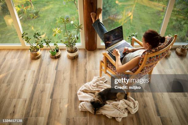 woman sitting on her terrace and using laptop for work - working from home imagens e fotografias de stock