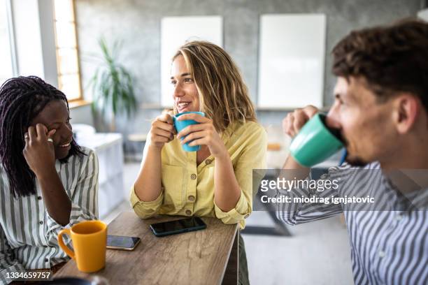 coworkers enjoying coffee break in open space workplace - coffee break office stock pictures, royalty-free photos & images