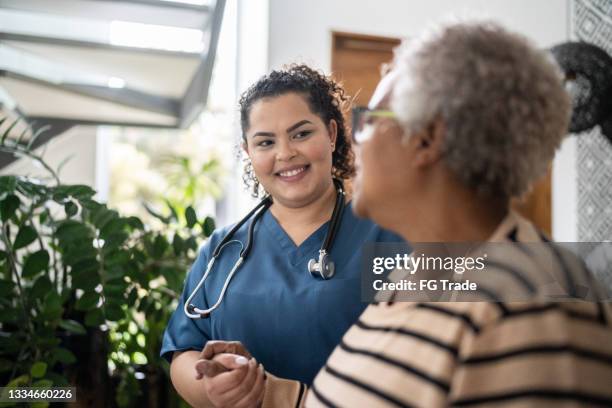 home caregiver helping senior woman walking at home - access stockfoto's en -beelden