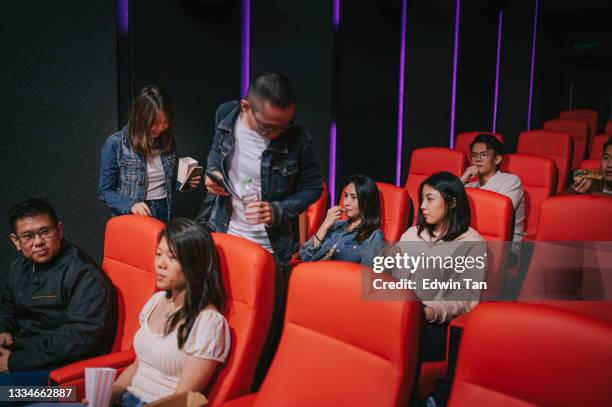 asian chinese couple late entering cinema trying to go through other audience to get to their seat during movie show time - couple entering the theater stock pictures, royalty-free photos & images