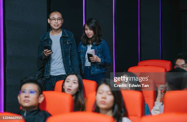 asian chinese couple late entering cinema trying to go through other audience to get to their seat during movie show time - couple entering the theater stock pictures, royalty-free photos & images