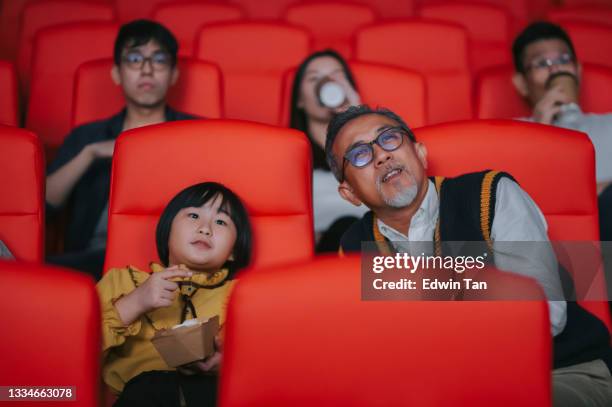 asian chinese active senior man and his granddaughter enjoy watching movie in cinema movie theatre - asian cinema bildbanksfoton och bilder