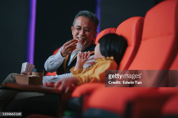 seitenansicht asiatischer chinesischer aktiver senior mann und seine enkelin genießen film im kino kino - asian cinema stock-fotos und bilder