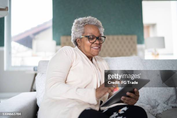 senior frau mit tablet pc zu hause - african american woman with tablet stock-fotos und bilder