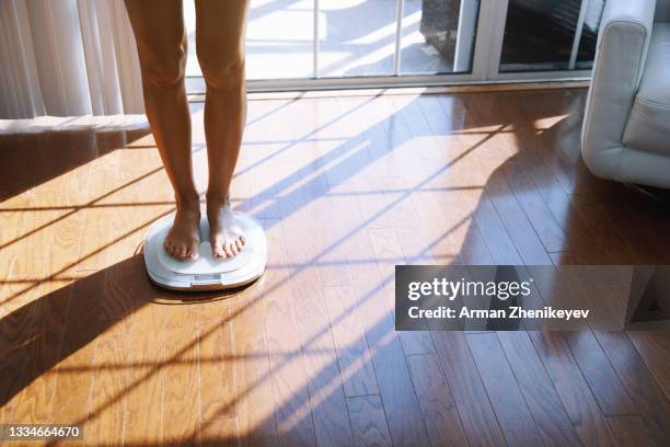 woman weighing herself on electronic balance at home - anoressia foto e immagini stock